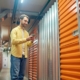 container-warehouse-smiling-young-bearded-man-light-shirt-jeans-with-smartphone-standing-near-closed-container-basement_259150-55027